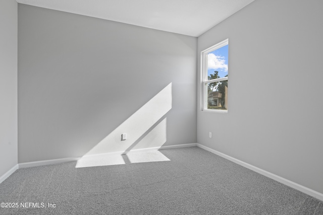 unfurnished room featuring carpet and baseboards