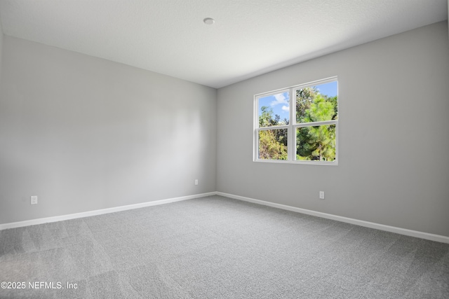 unfurnished room featuring carpet and baseboards