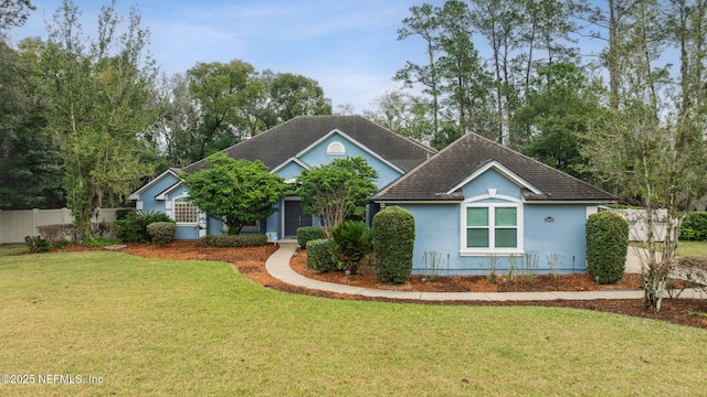 view of front of property featuring roof with shingles, a front yard, fence, and stucco siding