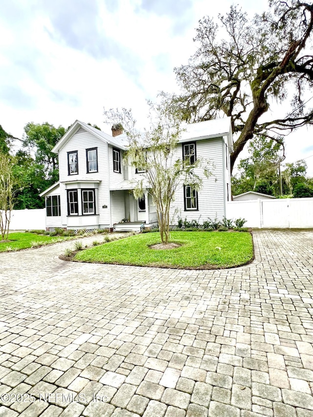 view of front facade featuring a front yard, fence, and a chimney