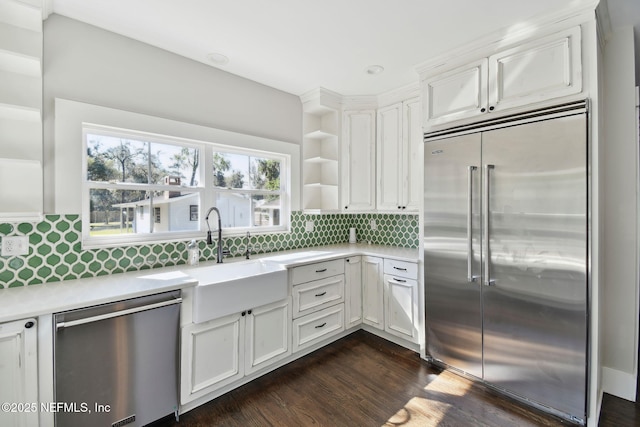 kitchen with open shelves, stainless steel appliances, light countertops, decorative backsplash, and a sink