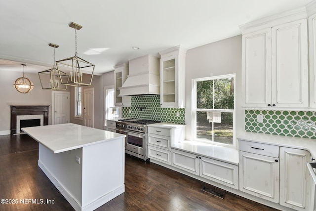 kitchen with high end stainless steel range, tasteful backsplash, light countertops, visible vents, and premium range hood