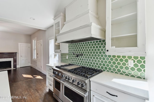 kitchen with premium range hood, light countertops, double oven range, white cabinetry, and backsplash