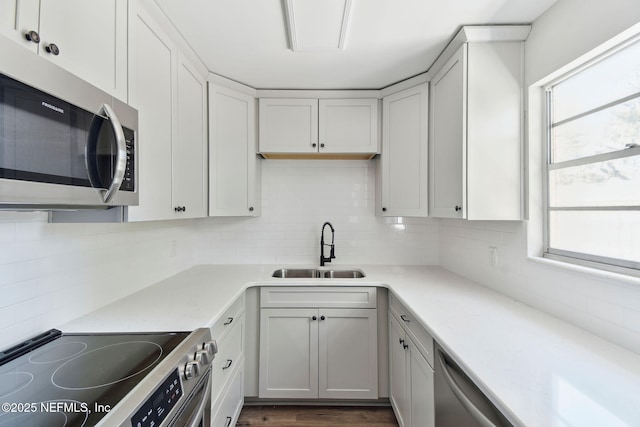 kitchen featuring stainless steel appliances, light countertops, a sink, and tasteful backsplash