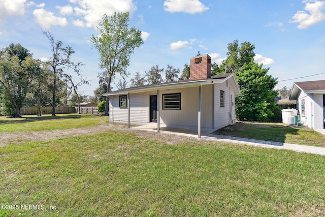 back of property with a patio area, a chimney, fence, and a yard