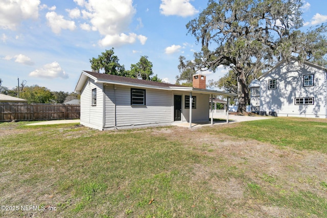 back of house with a patio area, fence, a chimney, and a lawn