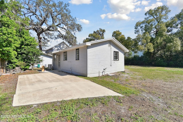 rear view of property with central air condition unit, a lawn, and a patio