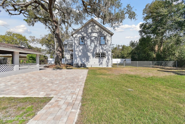 back of property with a lawn and fence