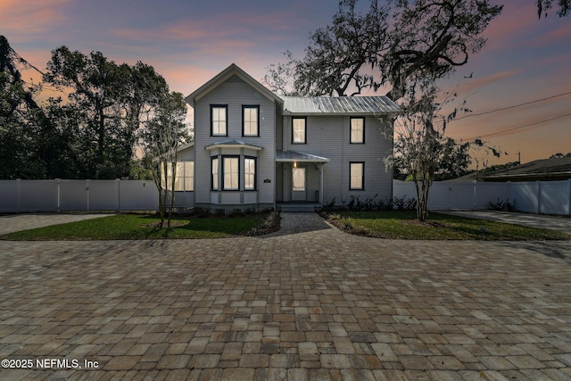 view of front of home featuring metal roof and fence