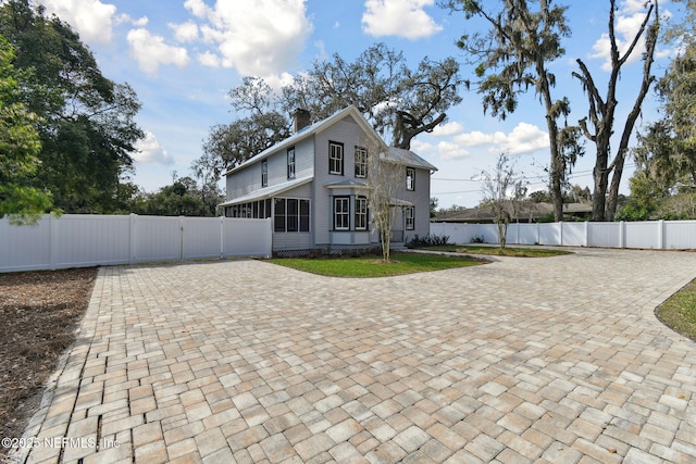 view of front facade featuring fence private yard, a sunroom, and a chimney