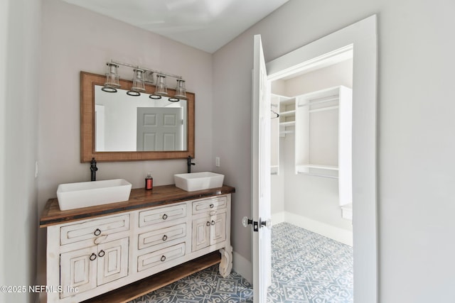 bathroom featuring a sink, baseboards, and double vanity