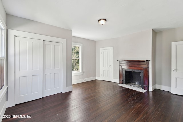 unfurnished living room with hardwood / wood-style flooring, a fireplace with flush hearth, and baseboards