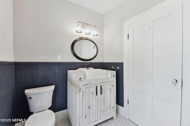 bathroom with wainscoting, vanity, and toilet