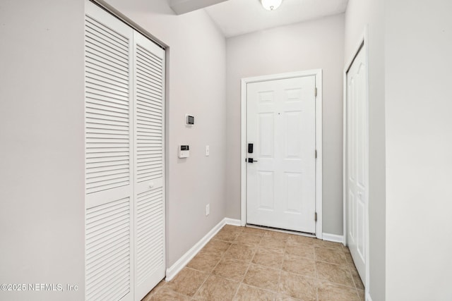 doorway featuring baseboards and light tile patterned floors