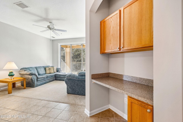 living area with ceiling fan, light tile patterned flooring, visible vents, baseboards, and built in desk