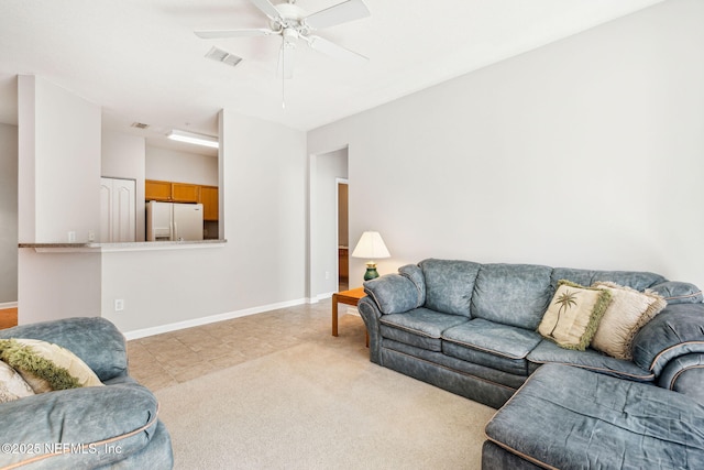 living area featuring baseboards, visible vents, a ceiling fan, and light colored carpet