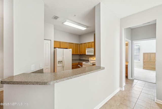 kitchen featuring white appliances, light tile patterned flooring, a peninsula, and baseboards