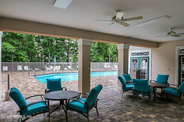 view of patio with ceiling fan, fence, and a community pool