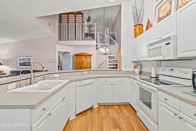 kitchen with light countertops, light wood-style flooring, white cabinets, a sink, and white appliances