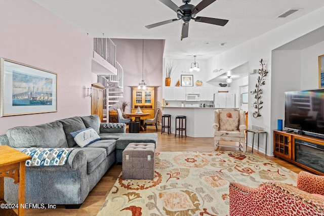 living room with light wood-style flooring, visible vents, and ceiling fan