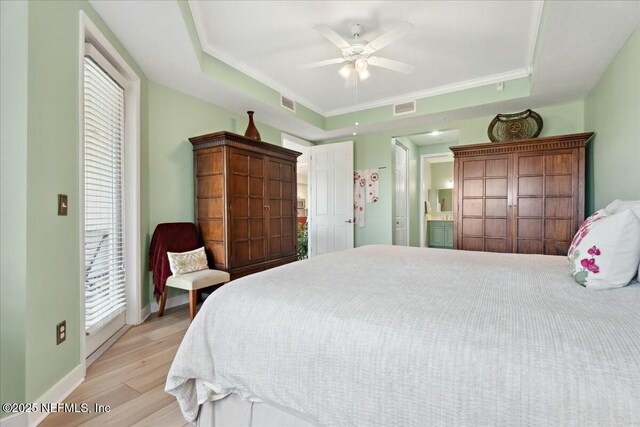 bedroom featuring baseboards, a raised ceiling, light wood-style floors, and visible vents