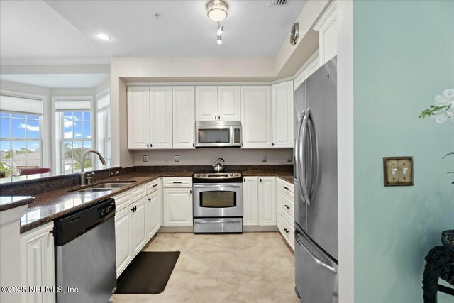 kitchen featuring dark stone countertops, recessed lighting, a sink, stainless steel appliances, and white cabinets