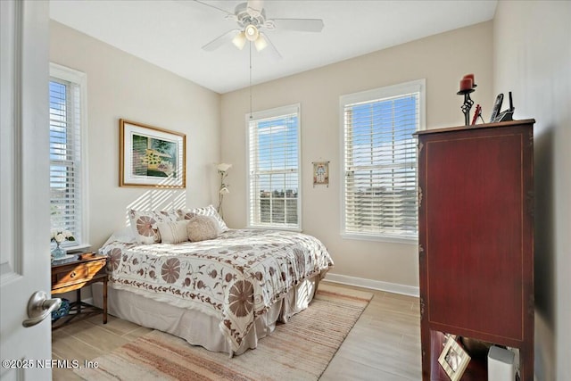 bedroom with a ceiling fan, light wood-style floors, and baseboards