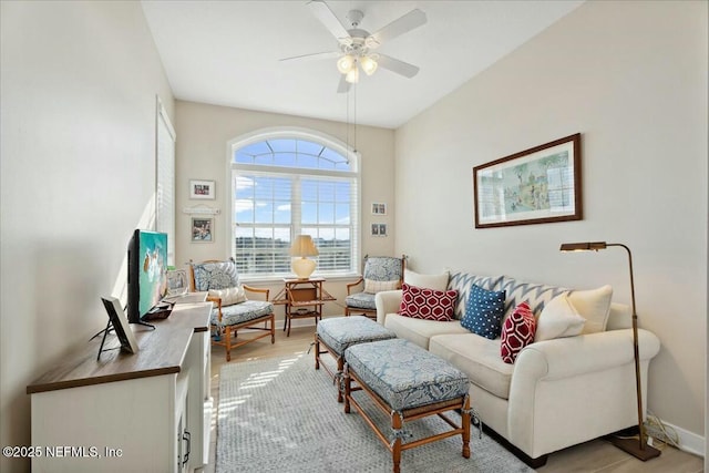 living area with baseboards, light wood-style floors, and a ceiling fan