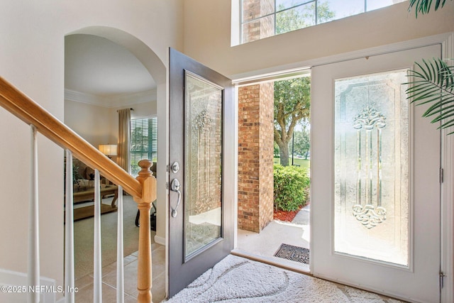 doorway to outside featuring arched walkways, french doors, ornamental molding, and stairs