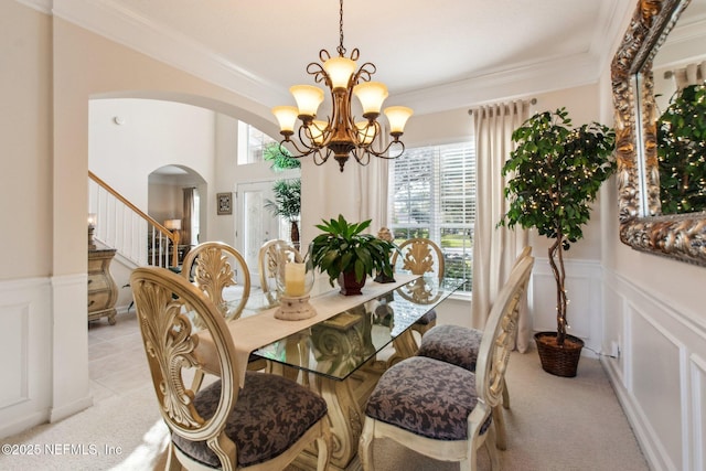 dining area featuring ornamental molding, arched walkways, wainscoting, and plenty of natural light