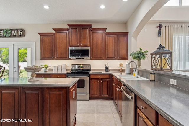 kitchen featuring light tile patterned floors, recessed lighting, stainless steel appliances, a sink, and dark countertops