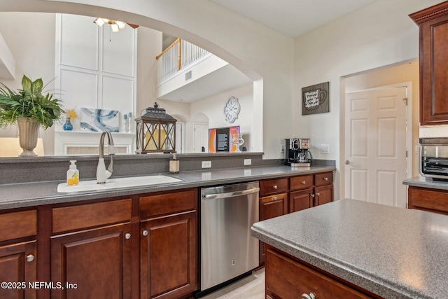 kitchen featuring a sink, dark countertops, arched walkways, and dishwasher