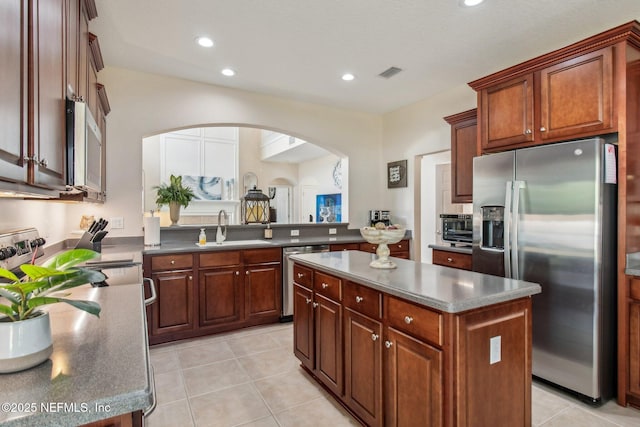 kitchen with visible vents, appliances with stainless steel finishes, a center island, a sink, and light tile patterned flooring