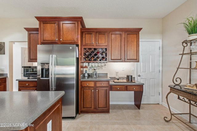 kitchen with dark countertops, brown cabinets, stainless steel fridge with ice dispenser, and light tile patterned floors