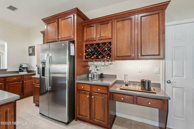 kitchen with visible vents, brown cabinetry, and stainless steel fridge with ice dispenser