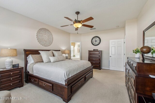 bedroom with ceiling fan, ensuite bath, visible vents, and light colored carpet