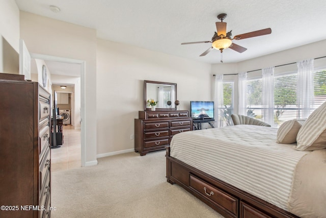 bedroom featuring washer / clothes dryer, light colored carpet, ceiling fan, and baseboards