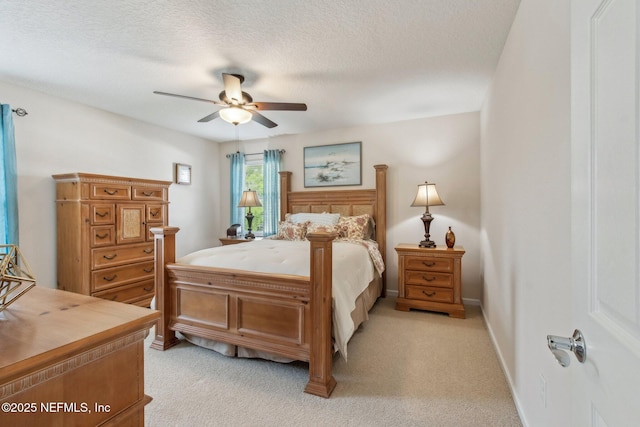 bedroom featuring light carpet, ceiling fan, a textured ceiling, and baseboards