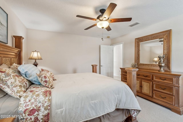 bedroom featuring a ceiling fan, visible vents, light carpet, and a textured ceiling