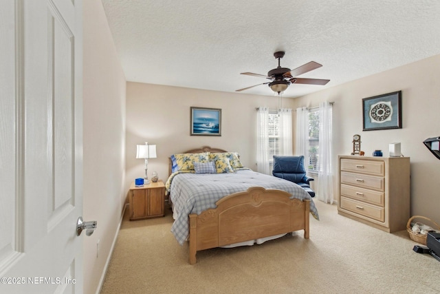 bedroom with baseboards, a ceiling fan, a textured ceiling, and light colored carpet