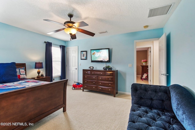 bedroom with a ceiling fan, light colored carpet, visible vents, and a textured ceiling