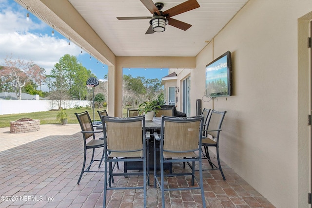 view of patio / terrace featuring an outdoor fire pit, outdoor dining area, fence, and ceiling fan