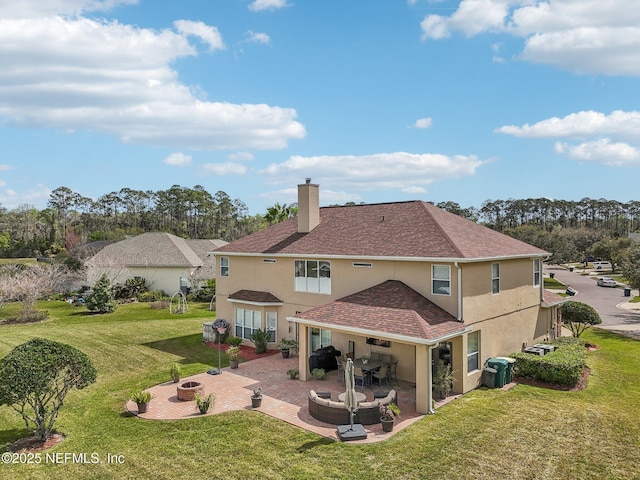 back of property featuring a fire pit, a lawn, a chimney, a patio area, and stucco siding