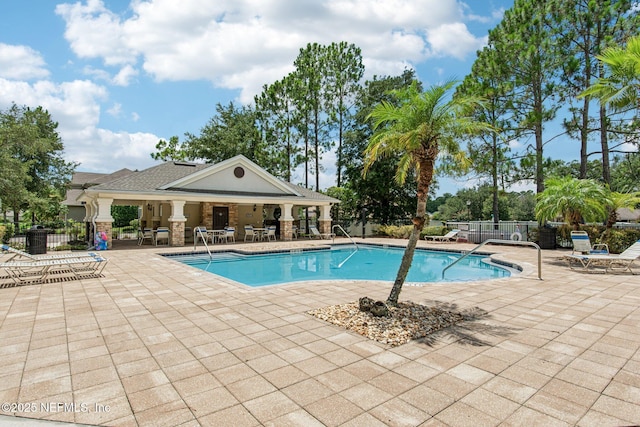 community pool with fence and a patio