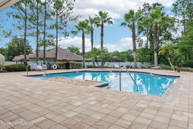 community pool with a patio area and fence