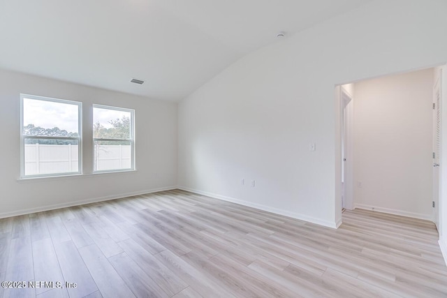 empty room with baseboards, lofted ceiling, visible vents, and light wood-style floors