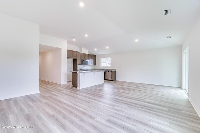 kitchen featuring a kitchen island, visible vents, open floor plan, appliances with stainless steel finishes, and light wood-type flooring