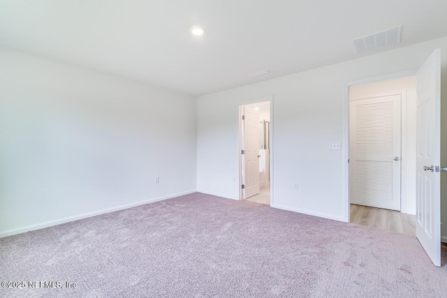 unfurnished bedroom featuring light carpet, connected bathroom, visible vents, and baseboards