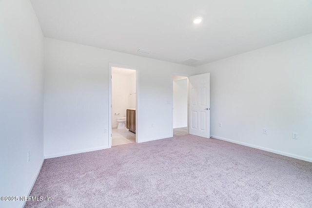 unfurnished bedroom featuring light carpet, baseboards, and ensuite bathroom