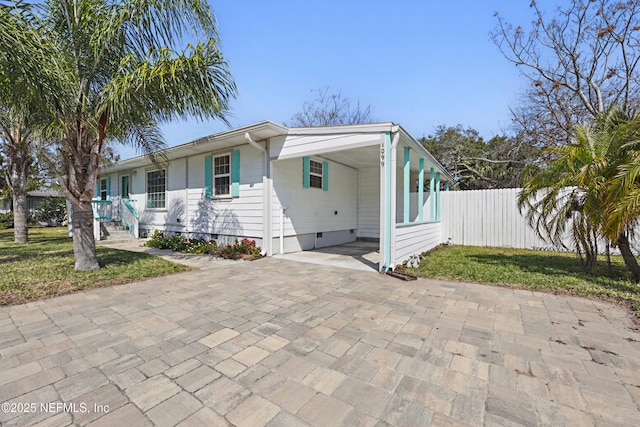 view of front of home featuring an attached carport, decorative driveway, fence, and a front lawn